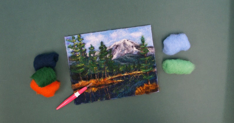 May include: A needle felting kit with a colorful mountain scene, a pink felting needle, and balls of wool in blue, green, orange, and dark green.