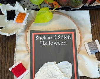 May include: A craft kit with the text "Stick and Stitch Halloween" on the front. The kit includes white felt shapes of a spider, ghost, and a pumpkin. The kit also includes red, orange, and gray embroidery floss.