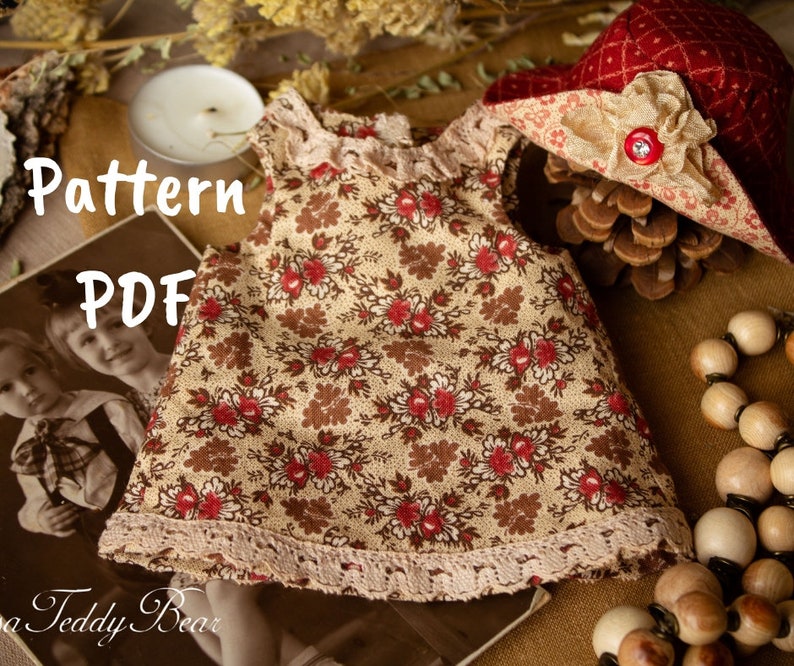 Puede incluir: Un patr&oacute;n PDF para un vestido de mu&ntilde;eca con estampado floral y ribete de encaje. El vestido es marr&oacute;n con flores rojas y tiene un ribete de encaje blanco. El patr&oacute;n tambi&eacute;n incluye un sombrero rojo y blanco con una cinta marr&oacute;n.