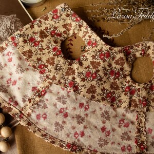 Puede incluir: Una tela marr&oacute;n y beige con un patr&oacute;n floral. La tela tiene dos grandes agujeros recortados. La tela est&aacute; sobre una superficie marr&oacute;n. El texto "Larisa Teddy Bear" es visible en la esquina superior derecha de la imagen.