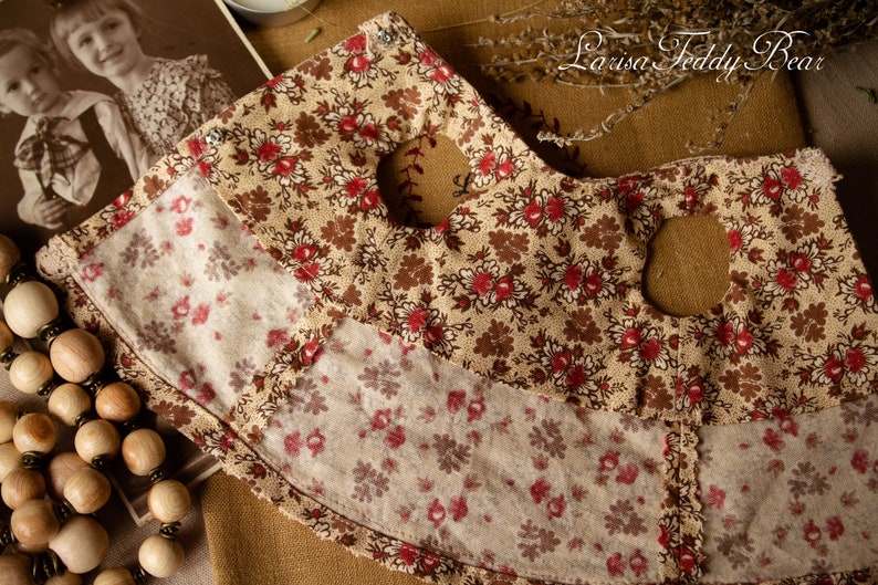 Puede incluir: Una tela marr&oacute;n y beige con un patr&oacute;n floral. La tela tiene dos grandes agujeros recortados. La tela est&aacute; sobre una superficie marr&oacute;n. El texto "Larisa Teddy Bear" es visible en la esquina superior derecha de la imagen.