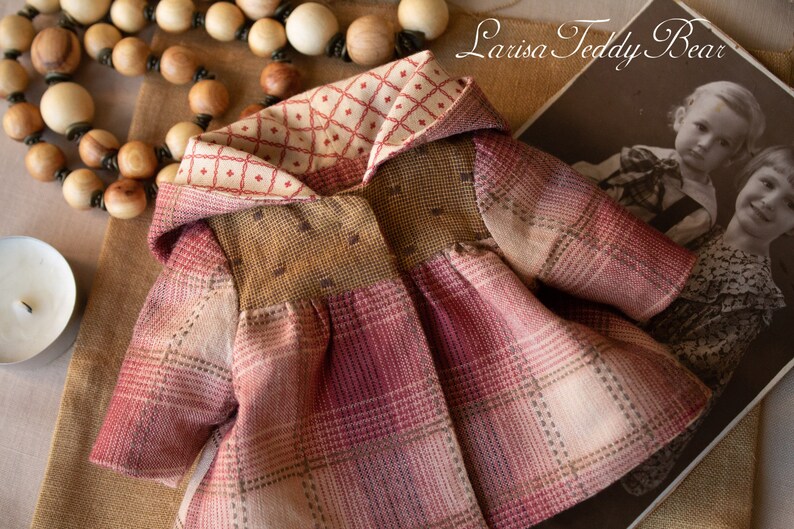 May include: A red, brown, and white plaid hooded jacket with a cream and red checkered lining. The jacket is made of a soft, textured fabric and has a vintage look.