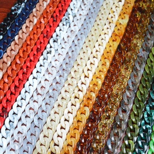 Può includere: Una varietà di maglie di catena di plastica colorate in diversi motivi e colori, tra cui bianco, rosso, arancione, marrone, verde e blu.