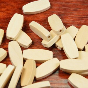 May include: A pile of natural wood oval beads, perfect for crafting projects. The beads are smooth and have a light brown color.