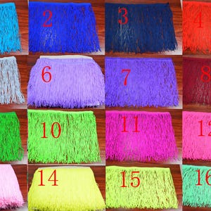 Pode incluir: Uma coleção de dezasseis acabamentos de franjas coloridas em várias tonalidades, incluindo azul, roxo, verde e rosa. Cada acabamento é retangular e densamente franjado, ideal para artesanato e design de figurinos. Os acabamentos estão numerados de 1 a 16.