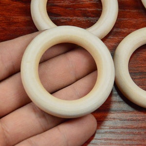 May include: A set of four unfinished wooden rings, ideal for crafting projects. The rings are smooth and have a natural wood colour.