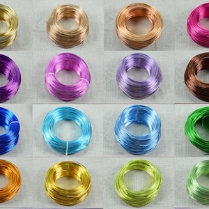 Könnte beinhalten: Eine Sammlung farbiger Drahtspulen in verschiedenen Farbtönen, darunter Gold, Bronze, Pink, Lila, Blau und Grün. Die Spulen sind ordentlich aufgerollt und in einem Rastermuster angeordnet, geeignet für Bastelarbeiten oder Schmuckherstellung.