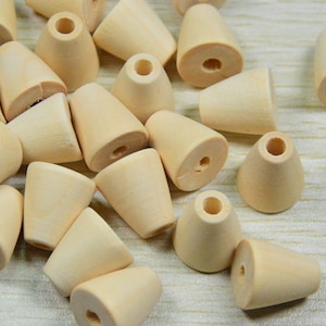 Könnte beinhalten: Ein Haufen naturfarbener Holzperlen in Kegelform mit einem Loch in der Mitte. Die Perlen sind hellbeige.