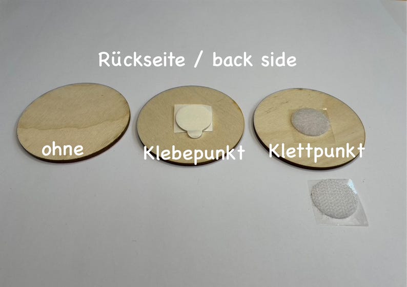 May include: Three round wooden discs with different backings. The first disc has no backing, the second disc has a sticky adhesive dot, and the third disc has a hook and loop fastener.