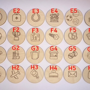 May include: Set of 36 wooden circles with different images and letters. The circles are arranged in a grid of six rows and six columns. Each circle has a letter and a corresponding image. The images include a yin yang symbol, a first aid kit, a necklace, a toolbox, a soccer ball, a construction vehicle, a soccer ball, a pair of scissors, a family, a hair clip, a pair of flip flops, a heart, a pencil, a test tube, a stack of papers, a store front, a marble, a basketball, a volleyball, an airplane, a glue bottle, a comb, an envelope, and a cat.