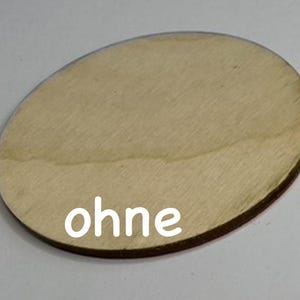 May include: A round, wooden disc with a smooth, light brown surface. The word "ohne" is printed in white on the disc.
