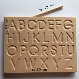May include: Wooden alphabet tracing board with raised letters for practicing handwriting. The board measures approximately 23 inches by 30 inches.