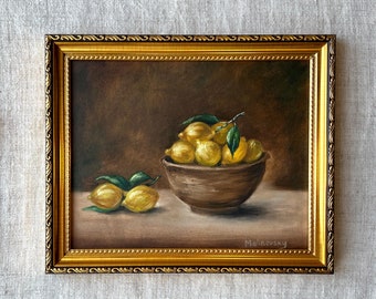 May include: A framed oil painting of a still life featuring a bowl of lemons with green leaves. The bowl is brown and the lemons are yellow. The painting is signed "Malinovsky" in the bottom right corner.