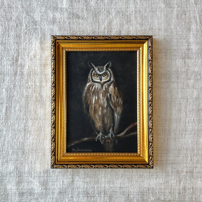 May include: A framed painting of an owl with brown and white feathers, perched on a branch. The painting is set against a dark background and signed "Malinevsky" in the bottom left corner.