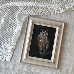 May include: A framed painting of an owl with brown and white feathers perched on a branch. The owl has yellow eyes and a dark background. The painting is signed "Malinowsky" in the bottom left corner.