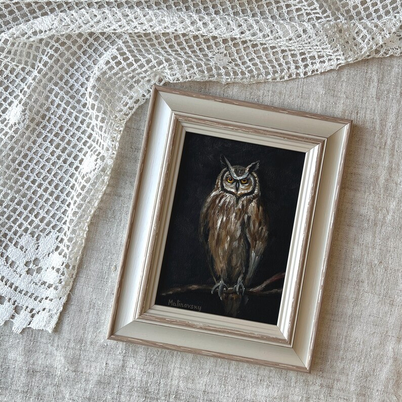 May include: A framed painting of an owl with brown and white feathers perched on a branch. The owl has yellow eyes and a dark background. The painting is signed "Malinowsky" in the bottom left corner.
