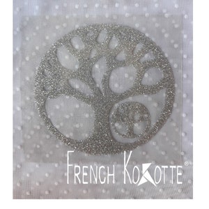 May include: A silver glitter tree of life design with a smaller tree of life inside the larger tree. The design is on a white background with small white dots.