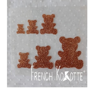 Peut inclure: Plusieurs formes d'ours en peluche scintillants de couleur cuivre, de différentes tailles. Les ours sont disposés sur un fond blanc à pois. Le texte "FRENCH KOKOTTE" est imprimé en blanc.