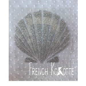 May include: A silver glitter seashell design on a white background with the text "French Kokotte" in white.