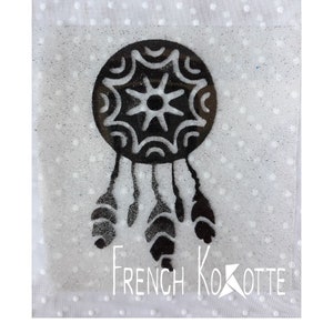 Peut inclure: Pochoir de capteur de rêves noir et blanc sur un fond blanc pailleté. Le pochoir présente un motif circulaire avec des plumes qui pendent du bas. Le texte "French Kotte" est visible dans le coin inférieur droit.