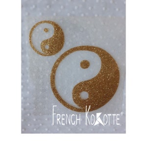 Peut inclure: Deux symboles yin yang en paillettes dorées sur un fond blanc avec un motif de pois blancs. Le symbole le plus grand est à droite et le plus petit à gauche. Le texte "French Kokotte" est en bas de l'image.
