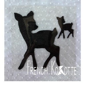 Peut inclure: Silhouette noire d'un cerf et de son faon sur fond blanc avec le texte "French Kokotte" en noir.