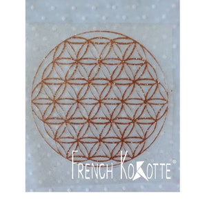 Peut inclure: Un autocollant transparent avec un motif géométrique de couleur cuivre, appelé Fleur de Vie, et le texte "French Kokotte" en bas.