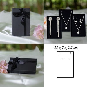 May include: Three black gift boxes with jewelry inside. The boxes are 11 x 7 x 2.2 inches. One box contains a pair of silver earrings with a large rhinestone. Another box contains a silver necklace with a large rhinestone pendant. The third box contains a pair of silver earrings with smaller rhinestones.