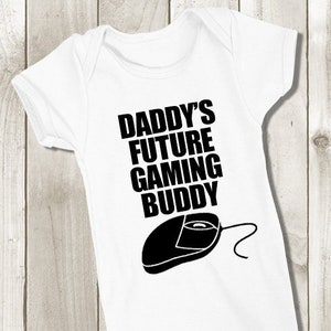 Könnte beinhalten: Weißer Baby-Strampler mit schwarzem Text "Daddy's Future Gaming Buddy" und einer schwarzen Silhouette einer Computermaus.