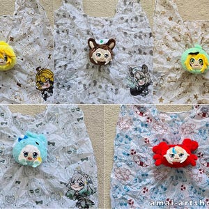 May include: Five reusable shopping bags featuring various anime-style character prints and matching plush character heads attached to the center. The bags have white backgrounds with repeating patterns of small icons and characters, with the text amai-artshop.com.