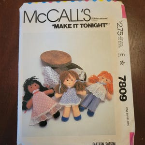 May include: McCall's sewing pattern envelope with the text "MAKE IT TONIGHT". The envelope features illustrations of three handmade dolls with various outfits. The pattern number is 7809.