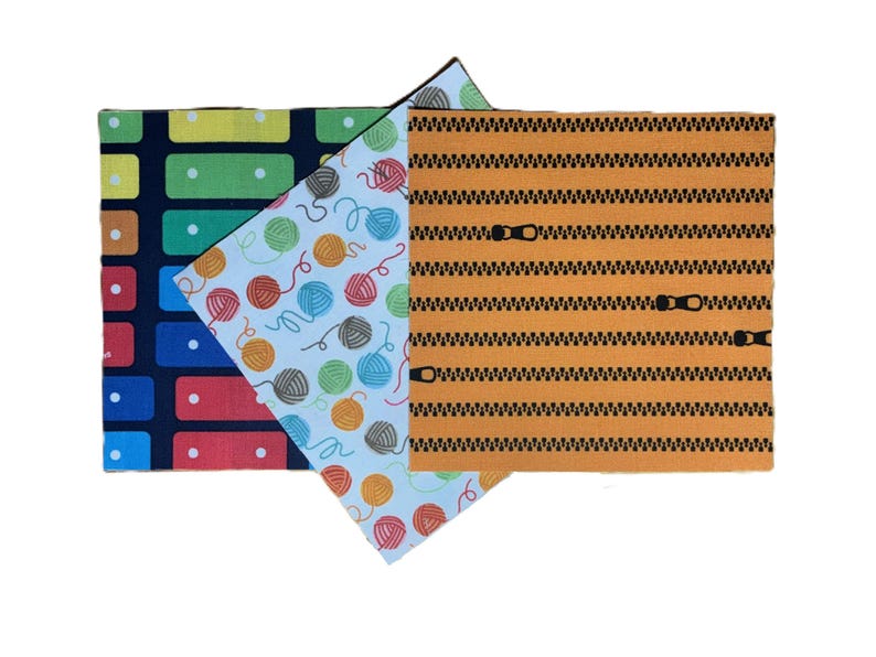 Puede incluir: Tres muestras de tela rectangulares con patrones distintos: un fondo azul oscuro con rect&aacute;ngulos coloridos, un fondo azul claro con ovillos de lana multicolores y un fondo naranja con motivos de cremalleras negras horizontales.