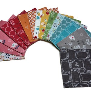 May include: A collection of square fabric swatches arranged in a fan shape. The patterns include various designs such as white flowers on pink, red honeycomb, tractors on orange, geometric shapes, yellow fruit, blue floral, and white mason jars on black.