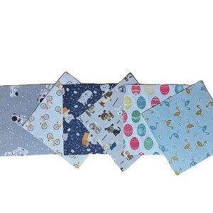 Puede incluir: Un juego de seis servilletas de tela cuadradas con diversos estampados, incluyendo astronautas sobre gris, bicicletas sobre azul claro, gatos sobre azul oscuro, perros sobre gris claro, huevos de Pascua coloridos y flamencos sobre azul.