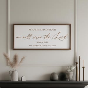 May include: A rectangular wooden framed sign with the text "AS FOR ME AND MY HOUSE we will serve the Lord JOSHUA 24:15 THE THOMPSON FAMILY - EST. 2025". The sign has a brown frame and a white background. It is displayed above a mantelpiece.