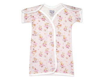 May include: A baby sleep sack with a pink background and a pattern of dancing bunny ballerinas in pink tutus. The sleep sack has short sleeves and a wrap-around design with white trim. The brand name "Perfectly Preemie" is visible.