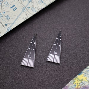 May include: Two black and white runway markings, each with the number "20" printed on them. The markings are triangular in shape and are made of metal.