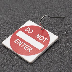 May include: Red and white 'Do Not Enter' sign earring with a silver hook.
