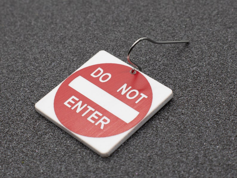 May include: Red and white 'Do Not Enter' sign earring with a silver hook.