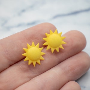 May include: Two yellow sun-shaped earrings with a starburst design.