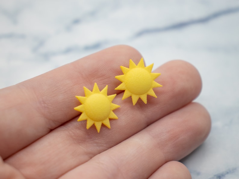 May include: Two yellow sun-shaped earrings with a starburst design.