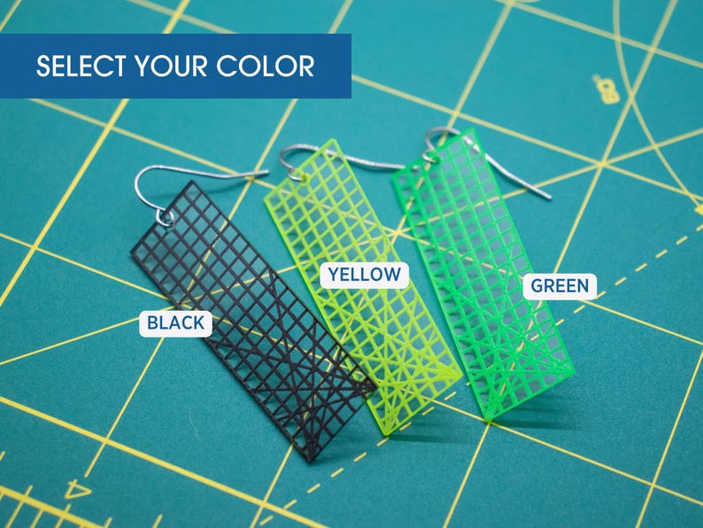 K&ouml;nnte beinhalten: Ohrringe in Schwarz, Gelb und Gr&uuml;n, jeweils mit einem Gittermuster, h&auml;ngen an silbernen Haken. Der Text "SELECT YOUR COLOR" steht oben. Die Ohrringe werden auf einer gr&uuml;nen Schneidematte pr&auml;sentiert.