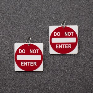 May include: Two white square signs with red borders and the text "DO NOT ENTER" in black letters.