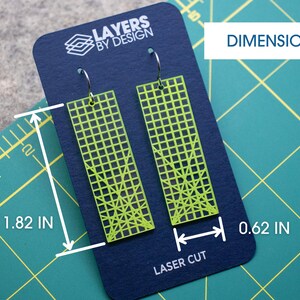 K&ouml;nnte beinhalten: Neongr&uuml;ne, lasergeschnittene Ohrringe mit Gittermuster, pr&auml;sentiert auf einer marineblauen Karte. Die Ohrringe sind 4,6 cm lang und 1,6 cm breit. Auf der Karte steht der Text "LAYERS BY DESIGN" und "LASER CUT".