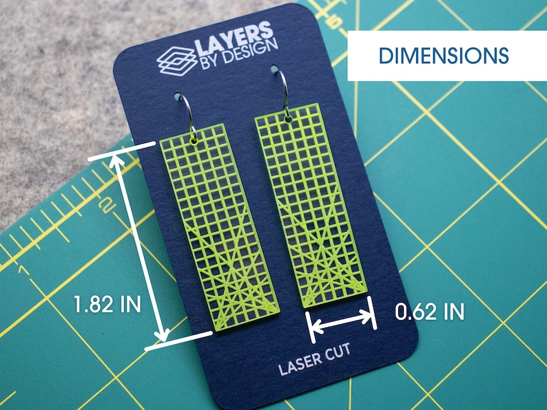 K&ouml;nnte beinhalten: Neongr&uuml;ne, lasergeschnittene Ohrringe mit Gittermuster, pr&auml;sentiert auf einer marineblauen Karte. Die Ohrringe sind 4,6 cm lang und 1,6 cm breit. Auf der Karte steht der Text "LAYERS BY DESIGN" und "LASER CUT".