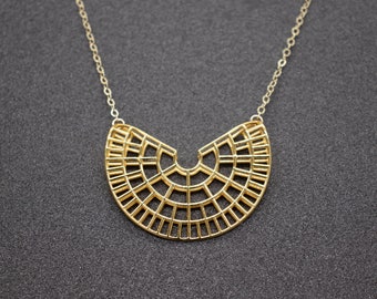 May include: A gold necklace with a geometric, fan-shaped pendant. The pendant is made of thin metal bars that create a delicate, openwork design.