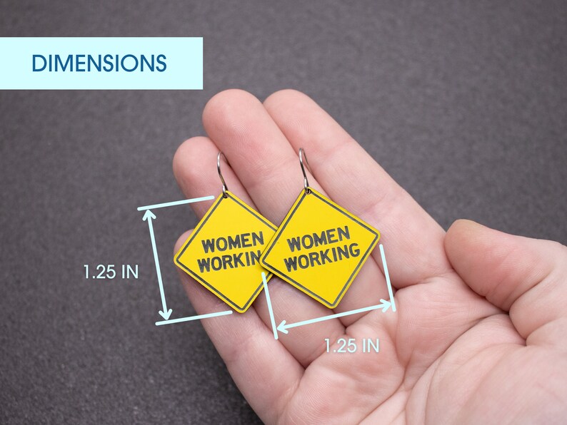 K&ouml;nnte beinhalten: Ein Paar gelbe, rautenf&ouml;rmige Ohrringe mit dem Text "Women Working" auf jedem Ohrring. Die Ohrringe haben einen Durchmesser von 1,25 Zoll.