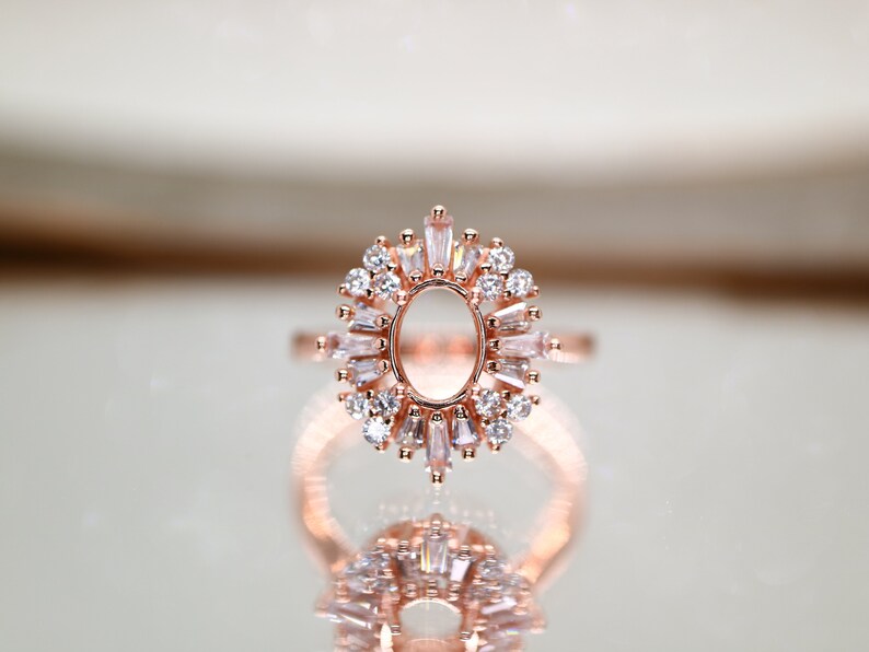 Puede incluir: Un anillo de oro rosa con una gran piedra ovalada central rodeada de piedras m&aacute;s peque&ntilde;as de forma baguette.