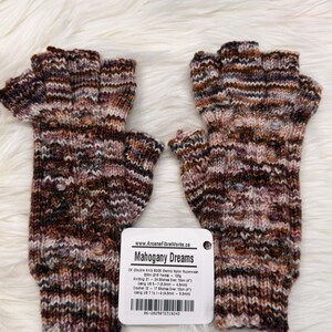 May include: Knitted fingerless gloves in a mix of brown, burgundy, and tan. The gloves have a textured design and a label that says "Mahogany Dreams". The gloves are made of DK (Double Knit) 80/20 Merino Nylon Superwash yarn.