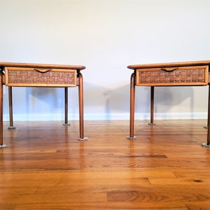 May include: Two wooden end tables with woven wicker drawers. The tables have a light brown finish and are on a hardwood floor.